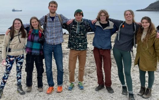 Seven students on a beach in walking gear