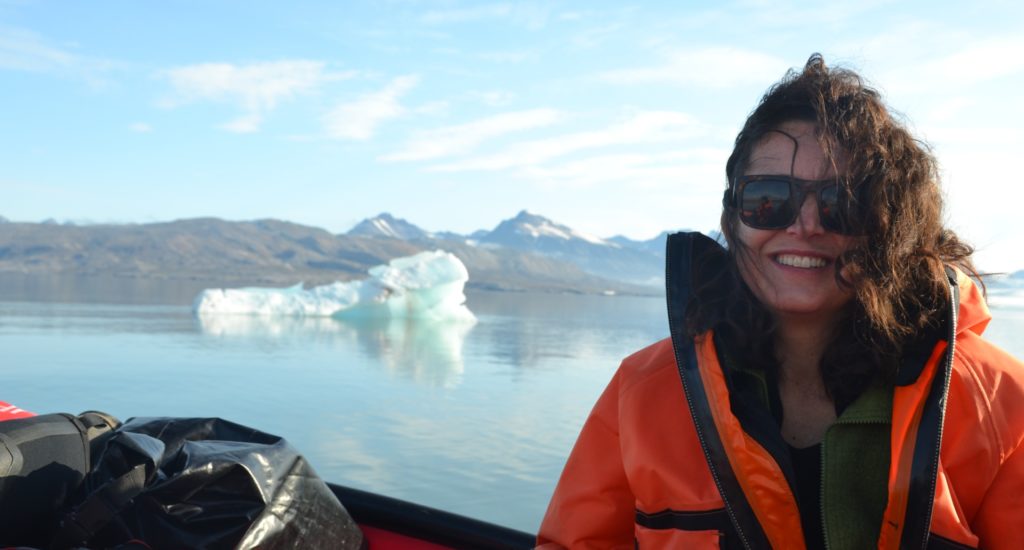 Angela Gallego-Sala in a boat, with water and ice visible behind, and land further in the distance