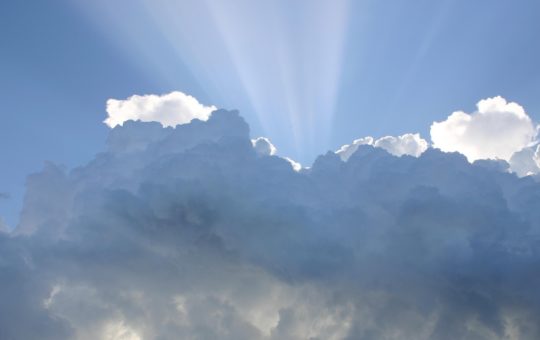 Beams of sunlight seen at the edges of white and grey clouds
